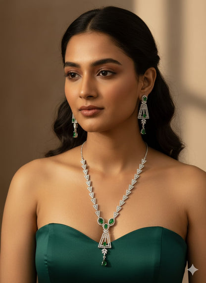 Elegant silver-tone necklace set featuring a line of clear stones, a geometric drop pendant with green gems, and matching earrings HJ43