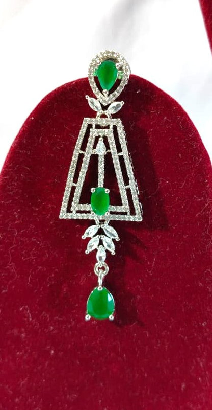 Elegant silver-tone necklace set featuring a line of clear stones, a geometric drop pendant with green gems, and matching earrings HJ43