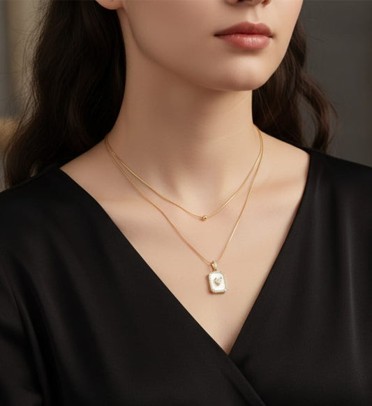 Gold double-layered  chain necklace with a bead and a white mother-of-pearl square pendant with a center heart HJ73